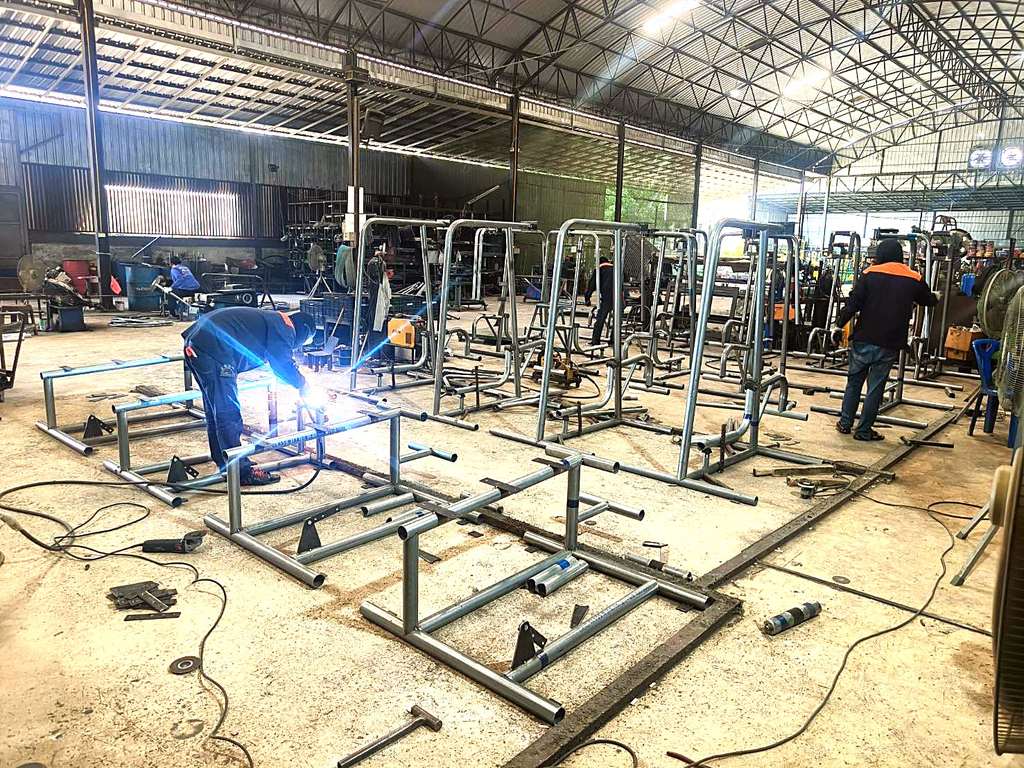 ช่างเชื่อมกำลังผลิตโครงเครื่องออกกำลังกายกลางแจ้งในโรงงาน Next Vision Engineering